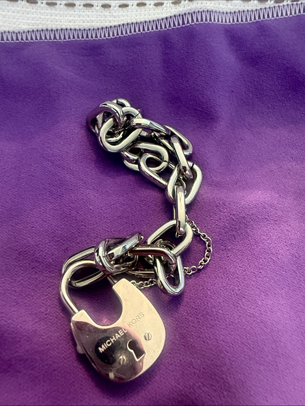Michael Kors Silver Padlock Link Bracelet on Purple Backdrop